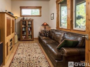 Bend townhouse for rent - A living room with a brown leather couch and a patterned rug.