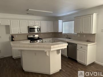 Tulare house for rent - A kitchen with white cabinets and a white island.
