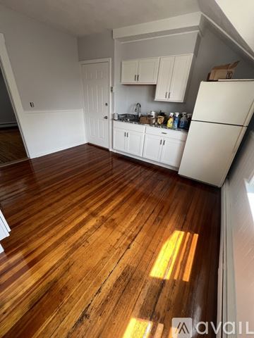 Cranston apartment for rent - A kitchen with white cabinets and a wooden floor.