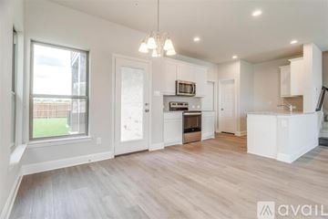 Mansfield house for rent - A spacious kitchen with white cabinets and a wooden floor.