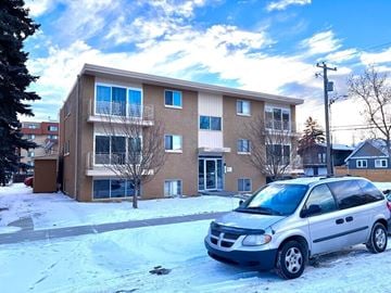Calgary apartment for rent - A silver Dodge van is parked in front of a two-story apartment building.