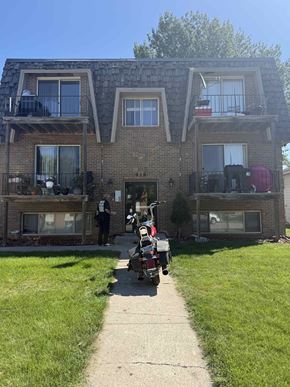 Moorhead apartment for rent - A person is standing outside a brick building with a red scooter.