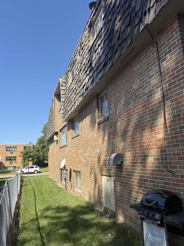 Moorhead apartment for rent - A brick building with a black grill on the lawn.