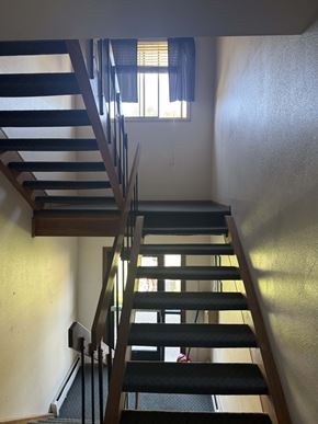 Moorhead apartment for rent - A staircase with a wooden handrail and black steps.