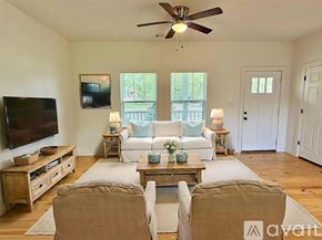 Brenham house for rent - A living room with a white couch, a wooden coffee table, and a flat-screen TV mounted on the wall.
