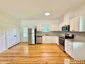 Brenham house for rent - A kitchen with wooden floors and white cabinets.
