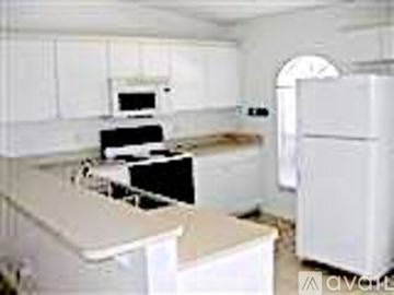 Cape Coral house for rent - A white kitchen with a refrigerator, sink, and oven.
