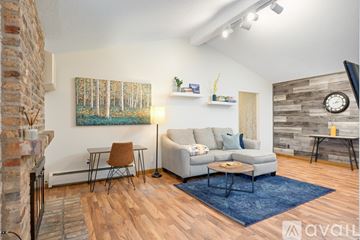 Hopkins condo for rent - A living room with a grey couch, a brown chair, a blue rug, and a painting on the wall.