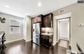 Irvine condo for rent - A kitchen with dark wood cabinets and a stainless steel refrigerator.