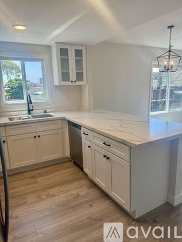 Laguna Beach apartment for rent - A kitchen with white cabinets and a wooden floor.