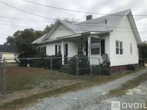 Goldsboro house for rent - A white house with a grey roof and a fence in front.