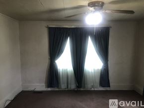 Goldsboro house for rent - A room with a ceiling fan and a window with curtains.