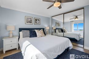 Carlsbad apartment for rent - A bedroom with a large bed, a ceiling fan, and a mirror showing another room.