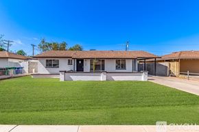 Mesa house for rent - A house with a white exterior and a brown roof is surrounded by a green lawn.