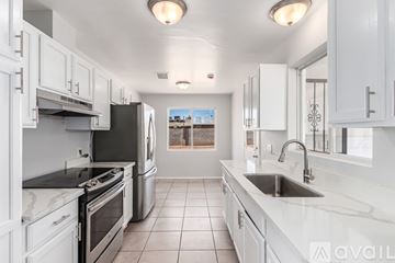 Mesa house for rent - A kitchen with white cabinets and black appliances.