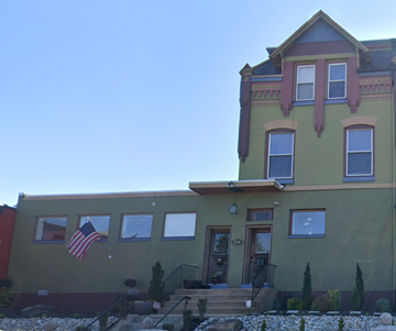 West Reading apartment for rent - A green house with a red door and a flag on the wall.