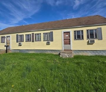 Charlestown house for rent - A yellow house with a brown roof and a red door.