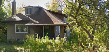 Ottawa house for rent - A small house with a brown roof and a chimney is surrounded by greenery.