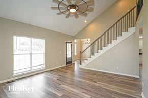 Hendersonville house for rent - A spacious room with wooden floors and a staircase leading to the upper level.