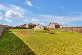 San Antonio house for rent - A grassy field with a fence and houses in the background.