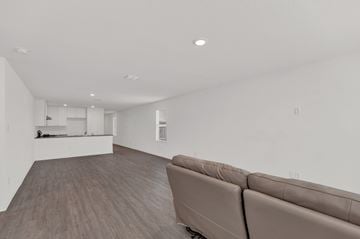 San Antonio house for rent - A living room with a brown couch and a kitchen in the background.