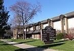 Elmhurst apartment for rent - A sign in front of a building with trees in the background.