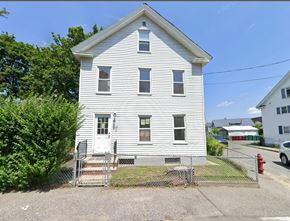 Lowell apartment for rent - A white house with a grey roof and a grey fence.
