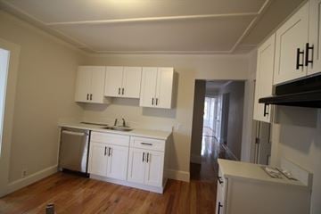 Lowell apartment for rent - A kitchen with white cabinets and a wooden floor.