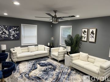 Suitland Silver Hill house for rent - A living room with a white sofa set and a ceiling fan.