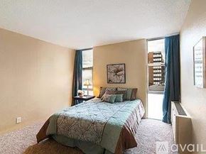 Denver condo for rent - A bedroom with a bed and a window with blue curtains.
