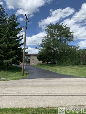 Cincinnati apartment for rent - A street view with a house and trees in the background.