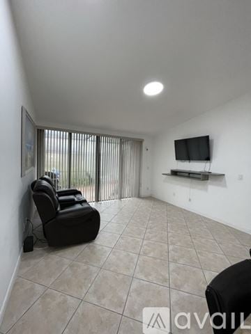 Pembroke Pines house for rent - A living room with a black chair and a flat screen TV mounted on the wall.