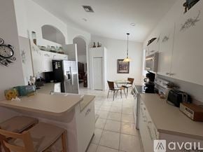 Delray Beach house for rent - A kitchen with white cabinets and a table with chairs in the middle.