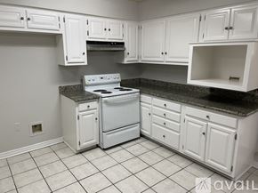 Mandeville house for rent - A kitchen with white cabinets and a granite countertop.