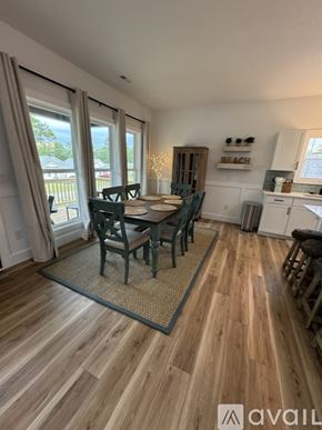 Oak Island house for rent - A dining room with a wooden floor and a table set for four.