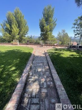Los Angeles house for rent - A stone pathway leads through a grassy area with trees in the background.