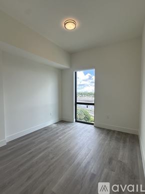 Oakland Park apartment for rent - A spacious room with wooden flooring and a sliding glass door leading to a balcony.