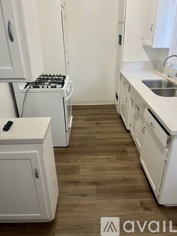 Santa Ana apartment for rent - A kitchen with white cabinets and a wooden floor.