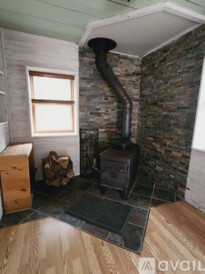 Marquette house for rent - A wood burning stove in a room with a stone wall.