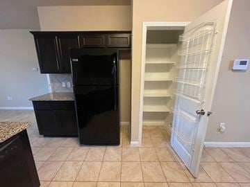 Pflugerville house for rent - A black refrigerator in a kitchen with a white door.