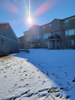Herriman house for rent - A sunny day in a snowy residential area with buildings on the left and apartment buildings on the right.