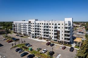 Leduc apartment for rent - A large white building with the words "NOW OPEN" on the side is surrounded by a parking lot with many cars.