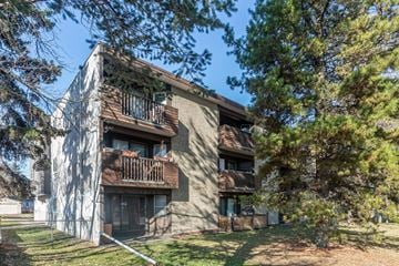 Edmonton apartment for rent - A building with a balcony and a tree in front of it.