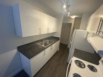 Edmonton apartment for rent - A kitchen with white cabinets and a black countertop.
