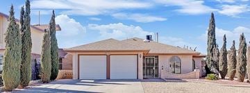 El Paso house for rent - A house with a brown roof and a white garage door is surrounded by trees.