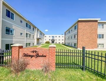 Edmonton apartment for rent - A brick sign that says "Whispering Gardens" is in front of a black fence.