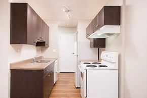Edmonton apartment for rent - A small kitchen with white appliances and brown cabinets.