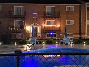 Riverside apartment for rent - A pool in front of a building with lights on.