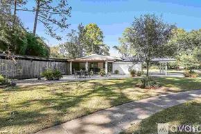 Baton Rouge house for rent - A house with a fence and trees in the background.