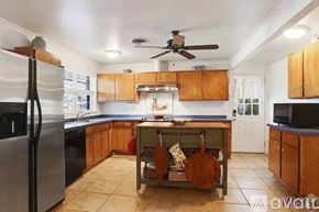 Baton Rouge house for rent - A kitchen with wooden cabinets and a black fridge.